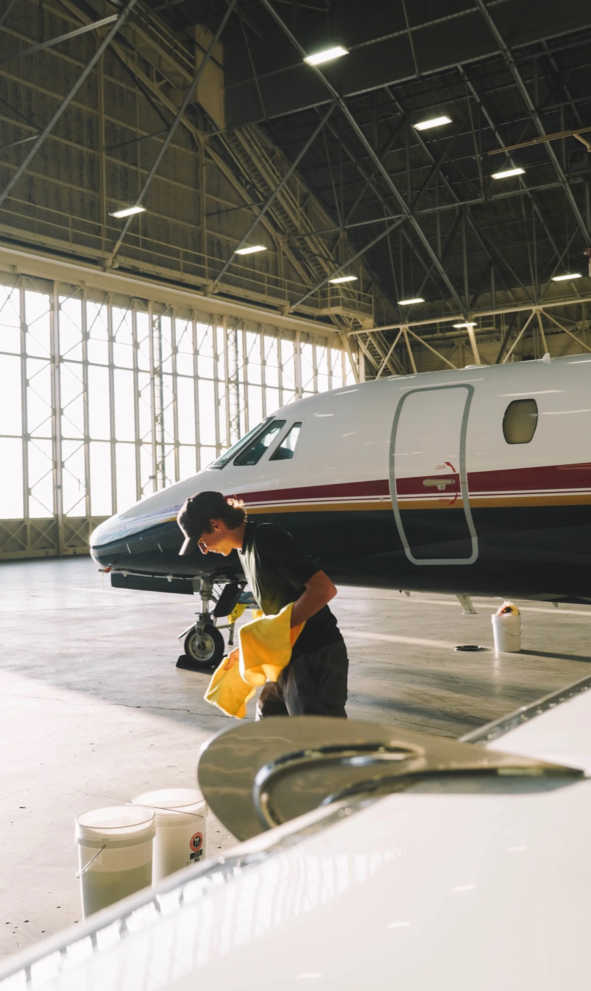 A detailer working on a business jet inside a hangar